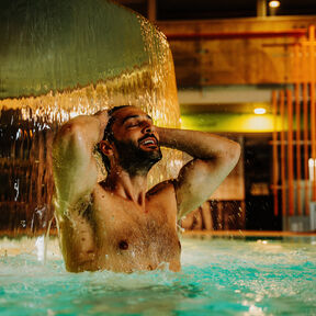 Mann unter Wasserfall in der Spreewald Therme